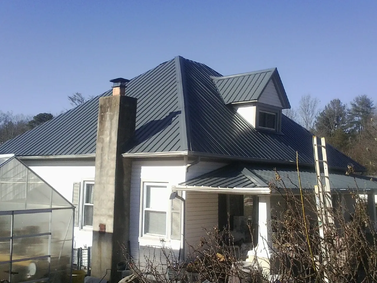 Dark blue standing seam metal roof on a white farmhouse with dormer — Slate & Tile Roof Repair by Roofing Brothers in Bealeton