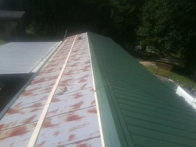 Old rusted panels beside newly installed green metal roofing — Wind Damage Roof Repair by Roofing Brothers in Bealeton