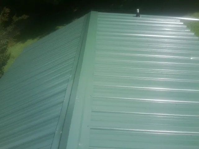 New green metal panels meeting at the ridge of a roof — Flat Roof Repair work by our crew in Bealeton
