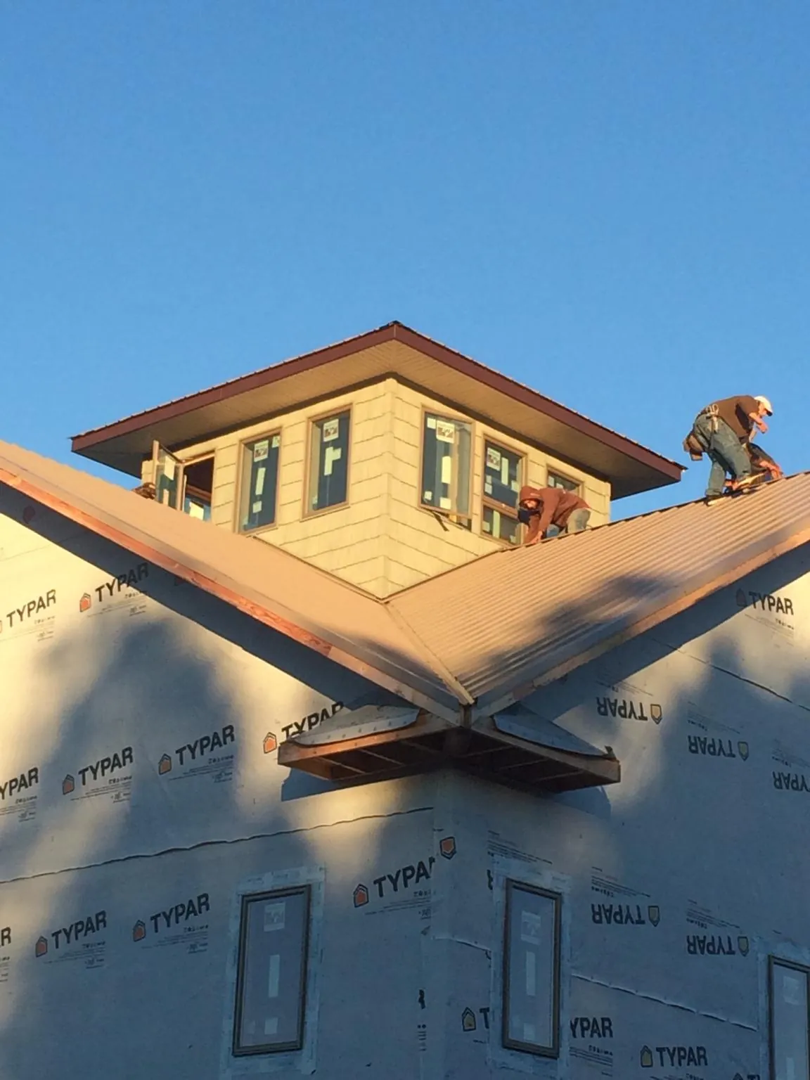 Roofers working around a rooftop cupola on a new metal roof at sunset — Roof Waterproofing in Bealeton by Roofing Brothers